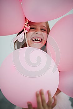 Portait of happy young girl with pink balloons