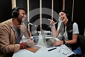 Portait of two happy radio hosts, young man and woman laughing while discussing various topics, moderating a live show