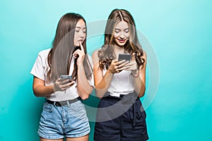 Portait of two mixed race women browsing internet or using mobile phones over blue background