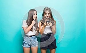 Portait of two mixed race women browsing internet or using mobile phones over blue background