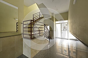 Portal of a house with polished granite floors, cream marble walls and red mental railings