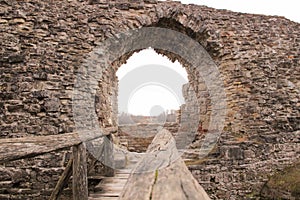 Portal in the medieval castle wall. The wall built of rocks and bricks with a window in the middle.