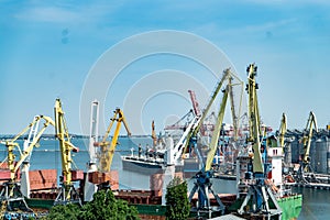 Portal port crane in the port. Logistics business. Huge cranes and containers, sunny summer day.