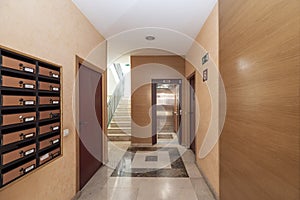 Portal of a residential apartment building with brass mailboxes, marble