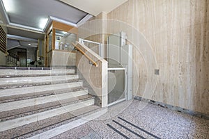 Portal of a residential building with marble stairs and a hydraulic lift for people with mobility problems