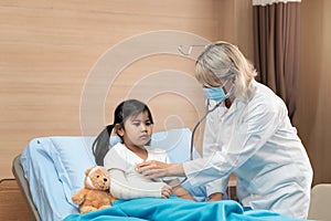 Portarit of smaile doctor pediatrician and little girl patient on bed photo