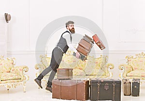 Porter, butler accidentally stumbled, dropping pile of vintage suitcases. Baggage insurance concept. Man with beard and