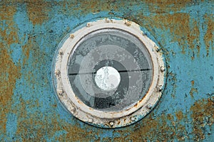 Porthole on the blue wall of the old ship.