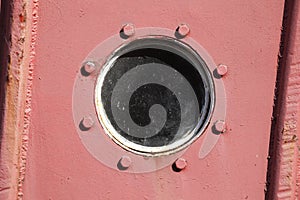Porthole on an old red ship\'s side