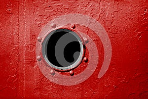 Porthole on red wall of old ship