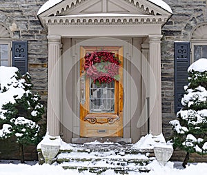 Portico entrance of house with snow covered bushes