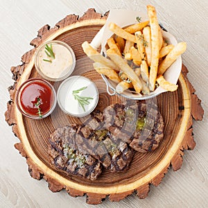 Portion of BBQ beef filet mignon with sauces and fried potatoes