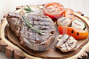 Portion of BBQ t-bone steak with sauce and grilled vegetables