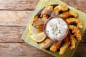 Portion of deep-fried golden avocado in breading with sauce and