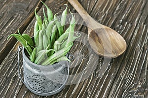 Portion of fresh green beans and spoon on a wooden background