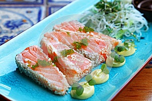 Portion of fresh raw salmon sashimi on blue plate