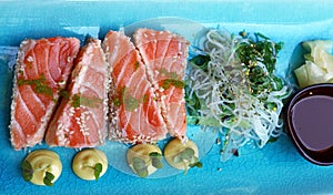 Portion of fresh raw salmon sashimi on blue plate