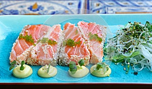 Portion of fresh raw salmon sashimi on blue plate