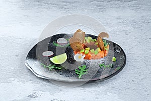 Portion of fresh salmon and avocado tartar on black plate