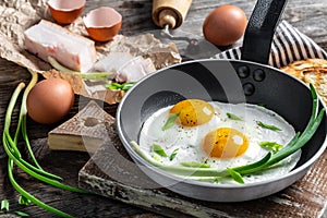 Portion of fried eggs with lard bacon in frying pan with pork lard, bread and green feathers onions. Ukrainian or belorussian