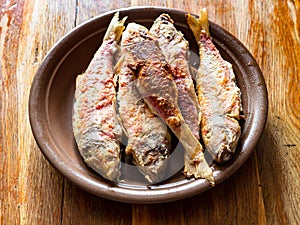 Portion of fried red mullet fish on ceramic plate