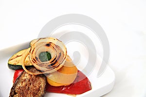 Portion of healthy grilled vegetables on square plate with white space background