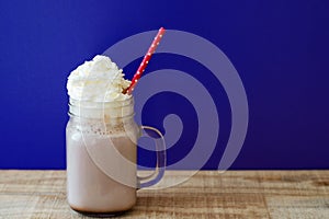 Portion of hot chocolate with white whipped cream in a glass jar