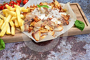 Portion of kebab Chicken duner gyros with french fries and garlic sauce on wooden board