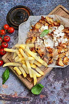 Portion of kebab Chicken duner gyros with french fries and garlic sauce on wooden board