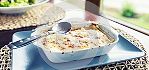 Portion of Lasagme bolognese in dish on table in restaurant