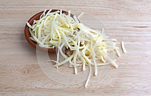 Portion of natural white mild cheddar cheese spilling from bowl