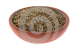 Portion of organic thyme leaf in a small terracotta bowl on a white background side view