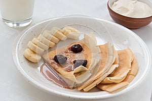 Portion pancakes with srawberry jam and bananas