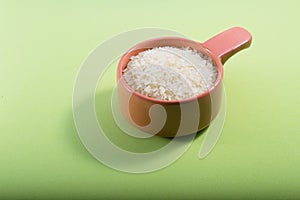 A portion of raw rice in a clay bowl on a green background