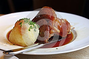 Portion of roasted pork shank with dumplings