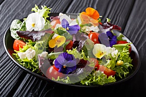 Portion of salad with edible flowers with fresh lettuce, spinach