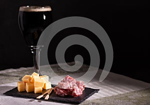 Portion of salami and cheese with a dark trappist beer