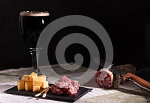 Portion of salami and cheese with a dark trappist beer