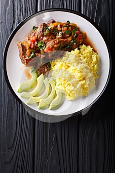 Portion of seco de chivo stewed goat meat with yellow rice and a