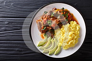 Portion of seco de chivo stewed goat meat with yellow rice and a photo