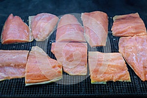 Portion slices of salmon cooking on the outdoor grille