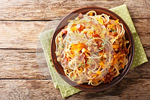 Portion of spaghetti with fried bacon, corn and cheese close-up on a plate. Horizontal top view