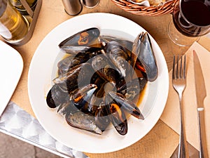 Portion of steamed mussels served with bay leaf on plate. Spanish dish mejillon la marinera photo