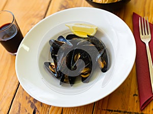 Portion of steamed mussels served on plate with piece of lemon. Spanish dish mejillon al vapor photo