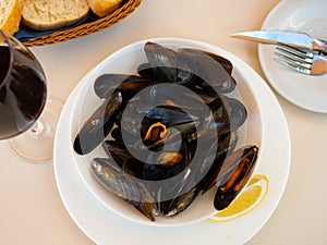 Portion of steamed mussels served on plate with piece of lemon. Spanish dish mejillon al vapor photo