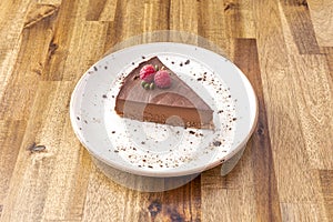 Portion of sweet potato cake like chocolate simile with some raspberries on a wooden table