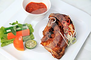 Portion traditional fried chicken with hot chili sauce and condiment, carrot, long bean, basil, lettuce, tomato, lime