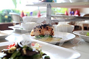 Portion of white meat with green peas on plate at restaurant