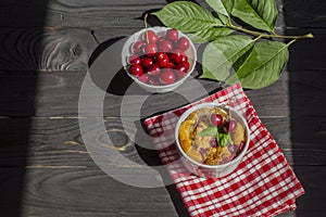 A portioned plate with clafoutis on a wooden background on a bright sunny day. Traditional French pie with cherry