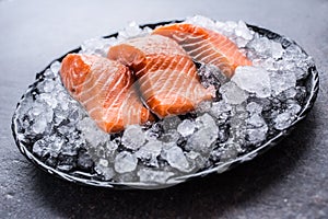 Portioned raw salmon fillets in ice on plate - Close-up